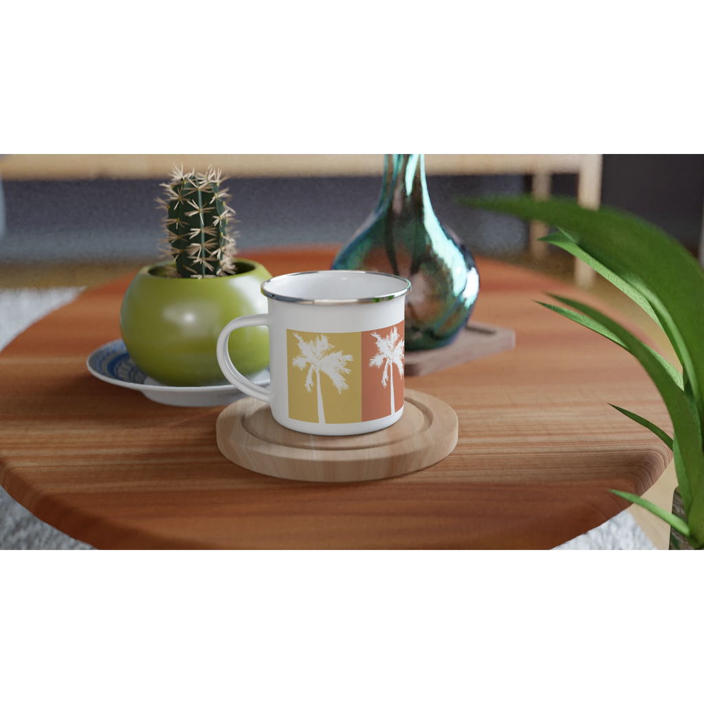 Weiße Emaille-Tasse mit Retro-Palmenmotiv in warmen Sommerfarben  auf einem Holztisch mit Kaktus und Vase