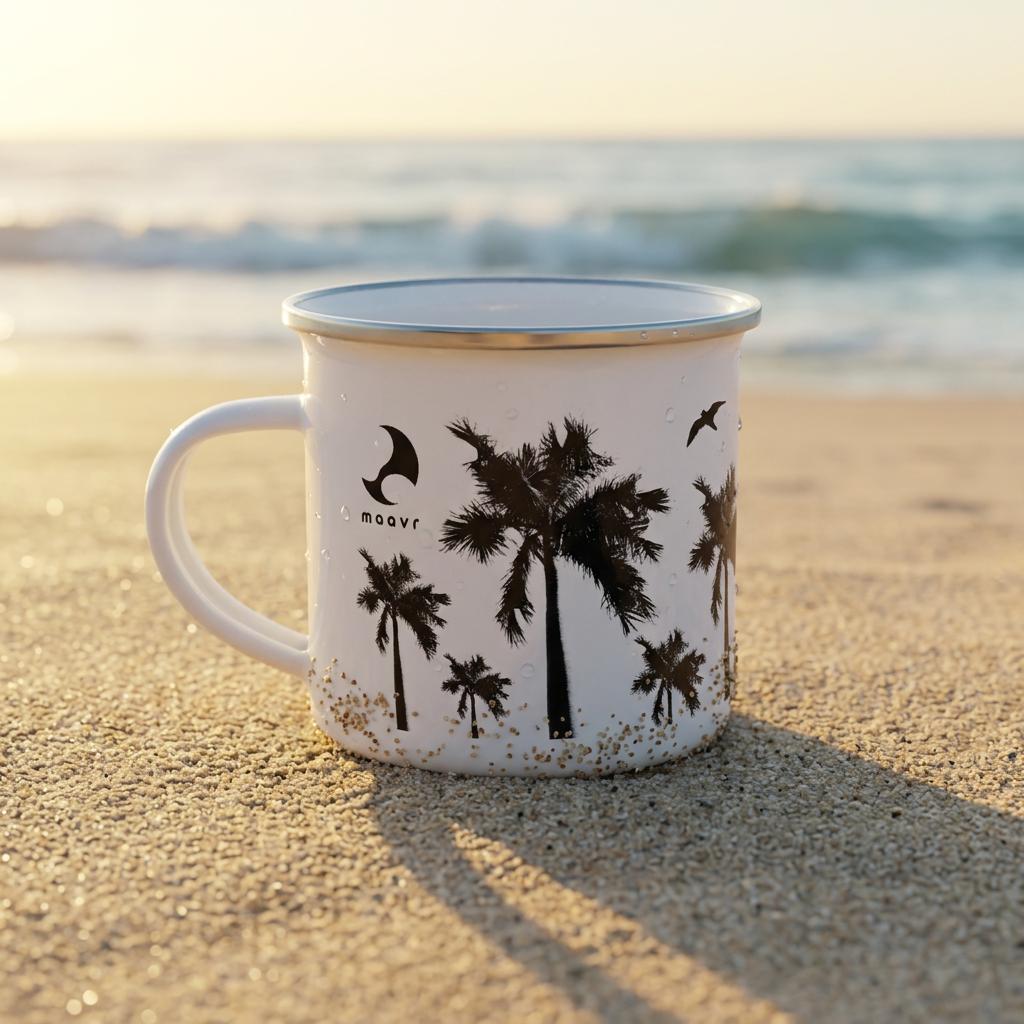 Weiße Emaille-Tasse mit silbernem Rand schwarzen Palmen-Motiven, maavr Logo an sonnigem Sandstrand
