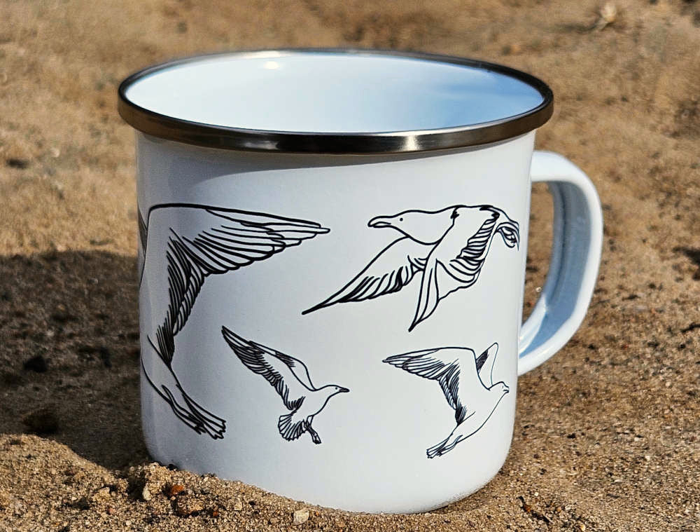 Weiße Emaille-Tasse mit silbernem Rand und Line-Art-Möwen-Motiv im Sand