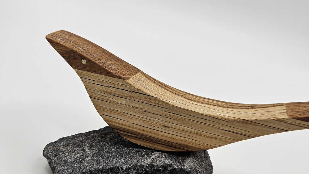 Detailansicht eines Holzvogels aus Eiche mit sichtbarer Holzmaserung auf Naturstein