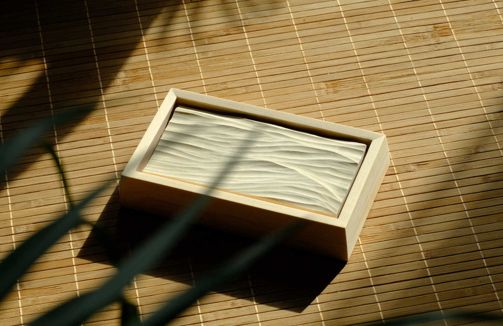 Gerahmtes Wellenrelief aus Holz hinter einer Pflanze