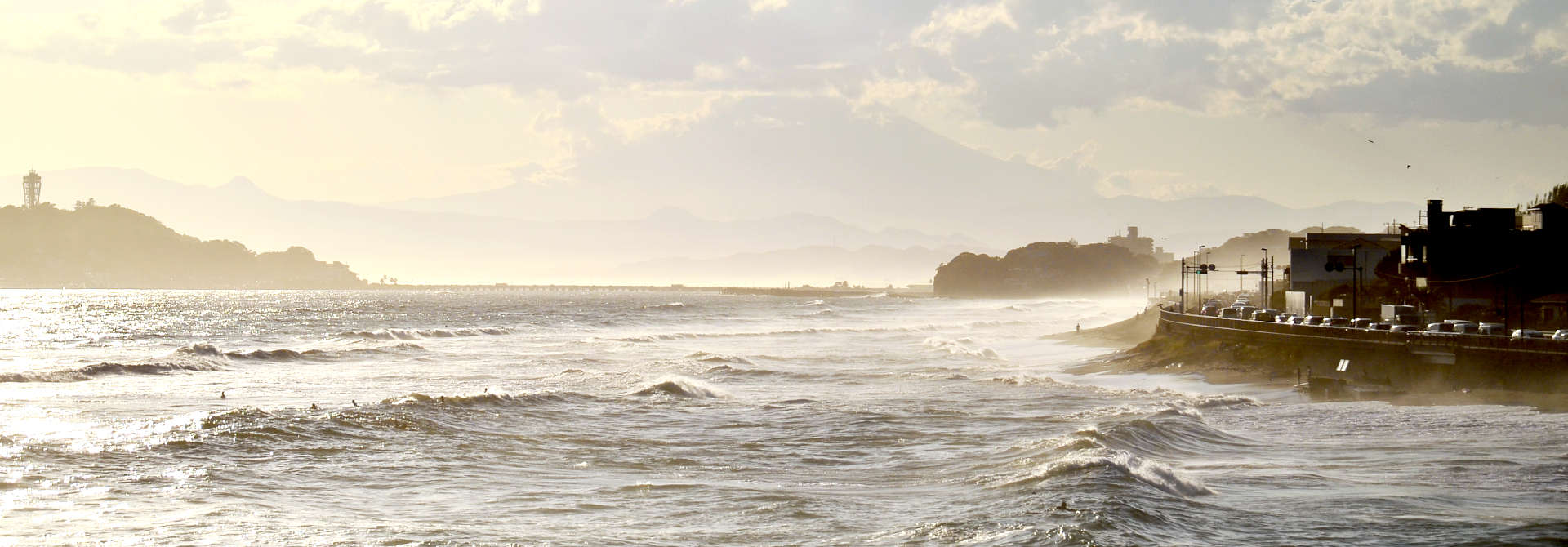 Küstenlandschaft mit Straße, Häusern und surfern im Wasser