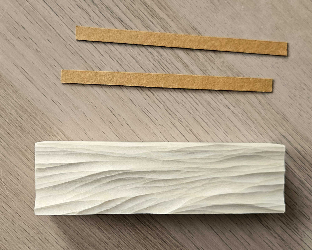 Handgeschnitzter Kartenhalter aus Holz mit Wellenrelief und Einlegern im Hintergrund