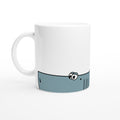 Weiße Keramiktasse mit blauem Cartoon-Hai-Motiv im unteren Drittel der Tasse 