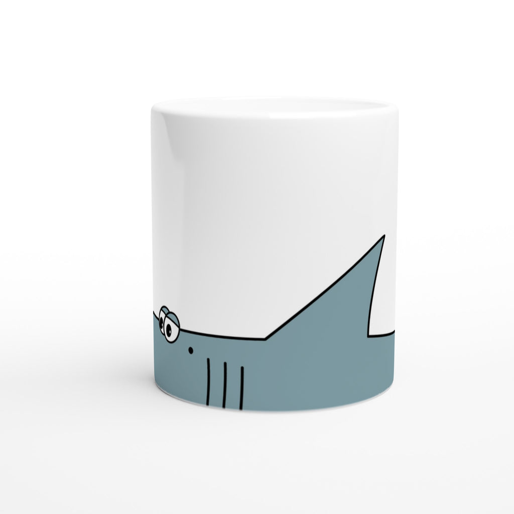 Weiße Keramiktasse mit blauem Cartoon-Hai-Motiv im unteren Drittel der Tasse 