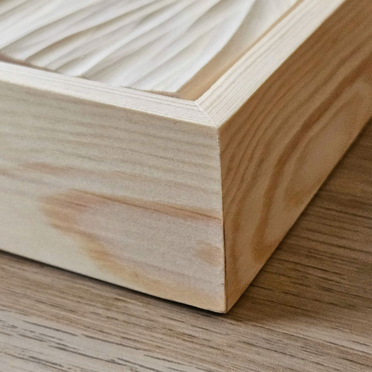 Detailaufnahme der  Ecke eines Holzrahmens mit geschnitztem Wellenrelief