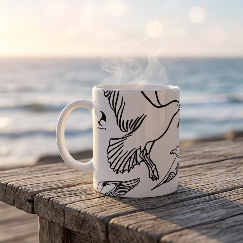 Weiße Keramiktasse mit Line Art Möwen-Motiv auf altem Holztisch am Meer