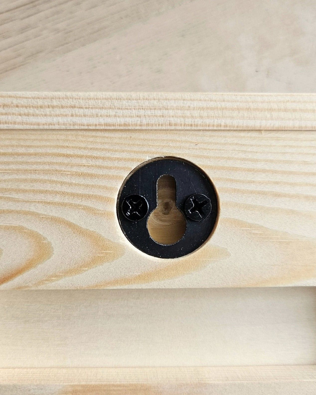 Rückseite des Wellenreliefs aus Holz mit schwarzer Schlüssellochaufhängung