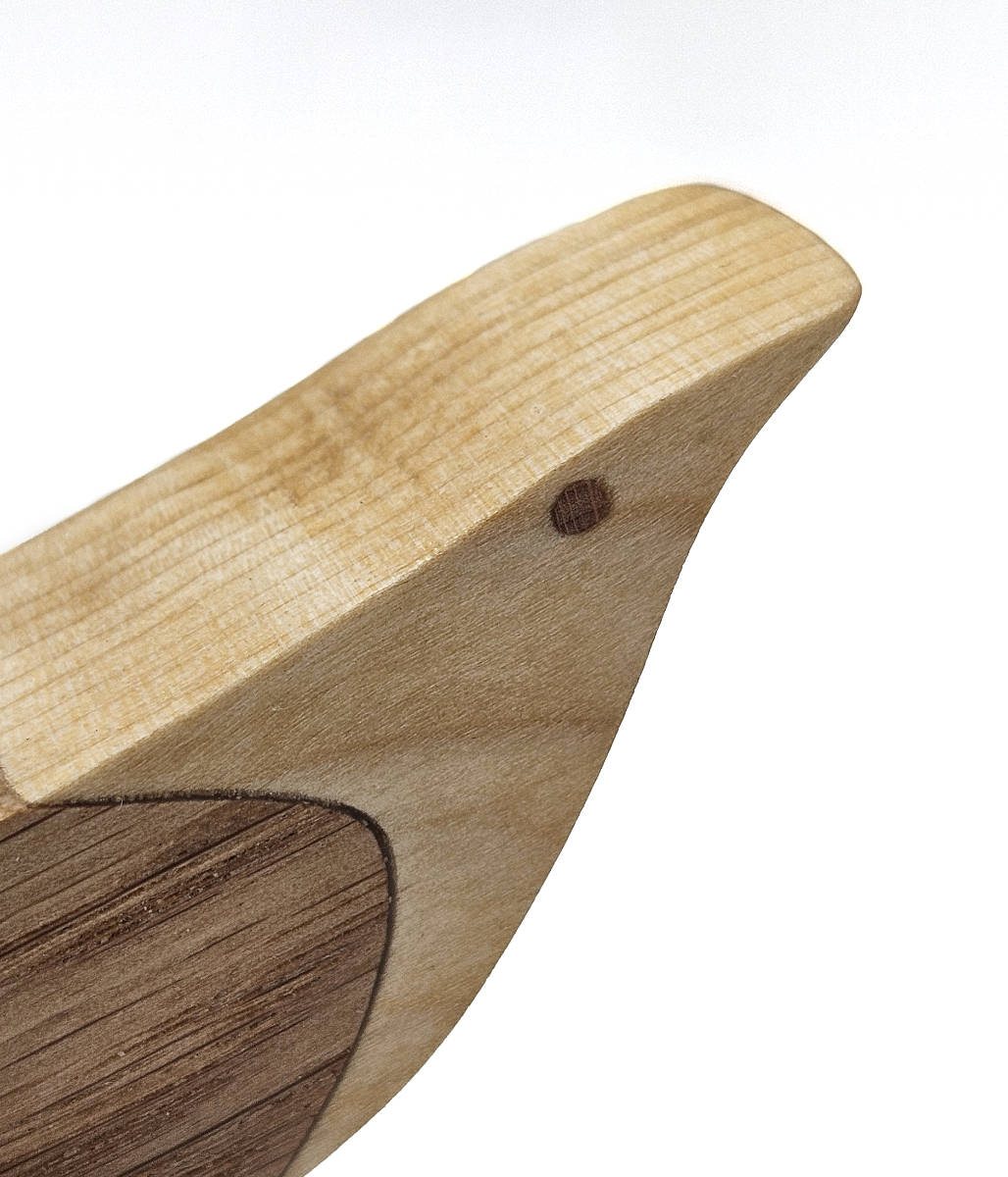 Detailansicht des handgefertigten Holzvogels aus Eiche und Birke mit sichtbarer Maserung und Intarsie