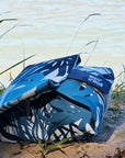 Snacktasche mit blauem  Pflanzenmuster, gefüllt und zusammengerollt am Ufer