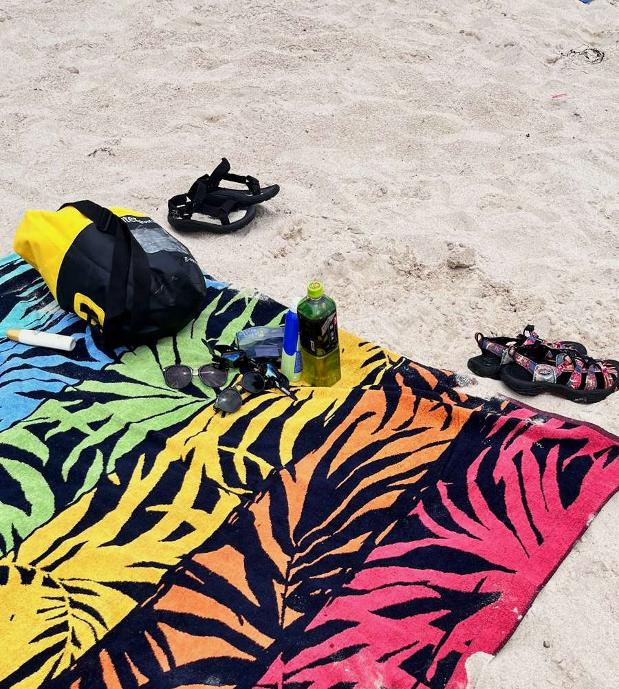 Mehrfarbiges Handtuch mit floralem Muster und Strandutensilien am Strand