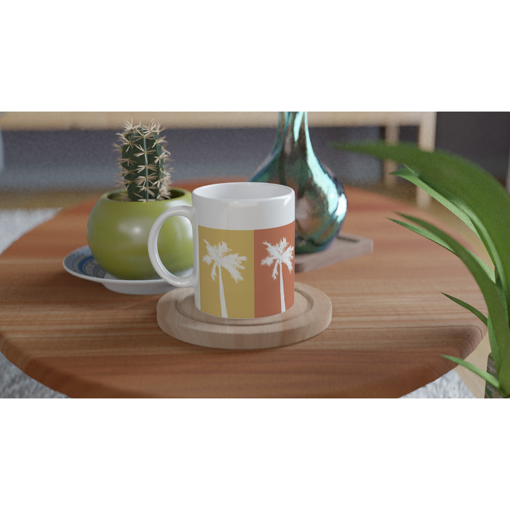 Bunte Tasse mit Palmen-Motiv auf einem Tisch mit Kaktus und Vase