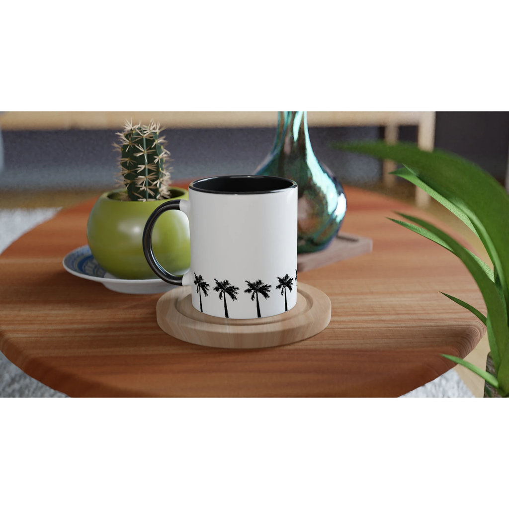 Keramiktasse mit umlaufender Palmenreihe, schwarzer Innenfläche und schwarzem Henkel auf Holztisch