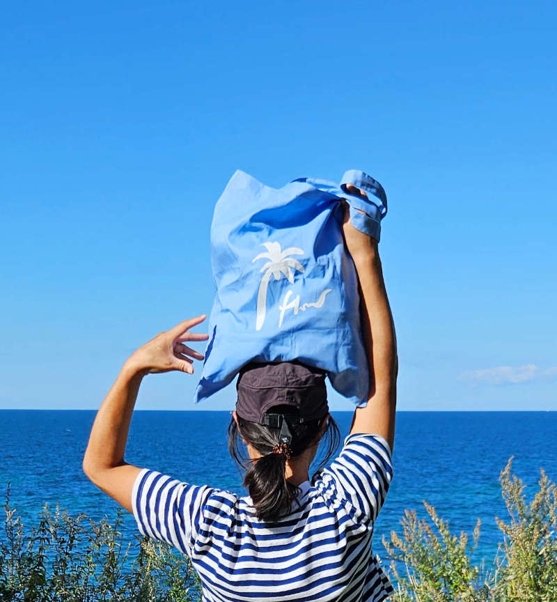 Blaue Tote Bag auf dem Kopf getragen am Meer an einem sommerlichen Tag 