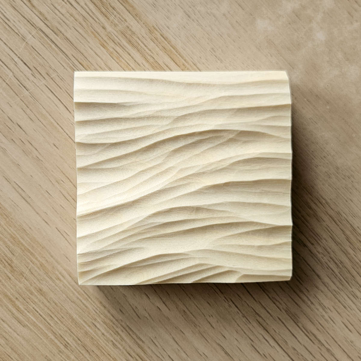 Handgeschnitztes Holzrelief mit Wellenmuster, auf einem Tisch liegend