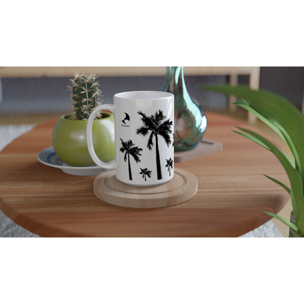Weiße XL-Keramiktasse mit Palmen-Motiven, maavr Logo, schwarzer Innenfläche und schwarzem Henkel auf einem Holztisch arrangiert mit einem Kaktus und einer Vase