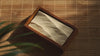Handgeschnitztes Wellenrelief in handgefertigtem Holzrahmen im Sonnenlicht zwischen Pflanzen in einer Wohnung